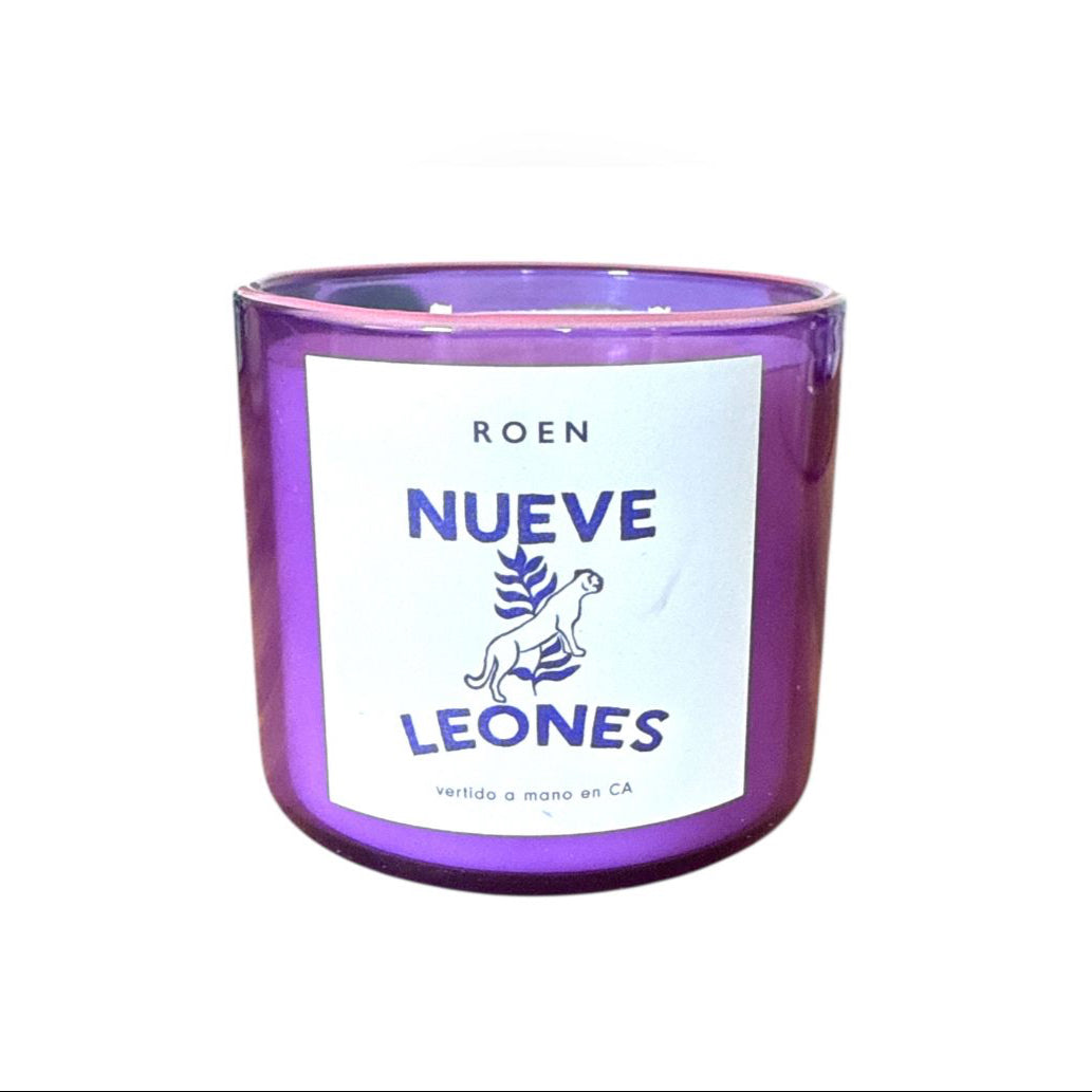 A purple glass candle with a white label that reads 'NUEVE LEONES'.