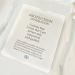White candle with a 'Protection Affirmation' card on a white background