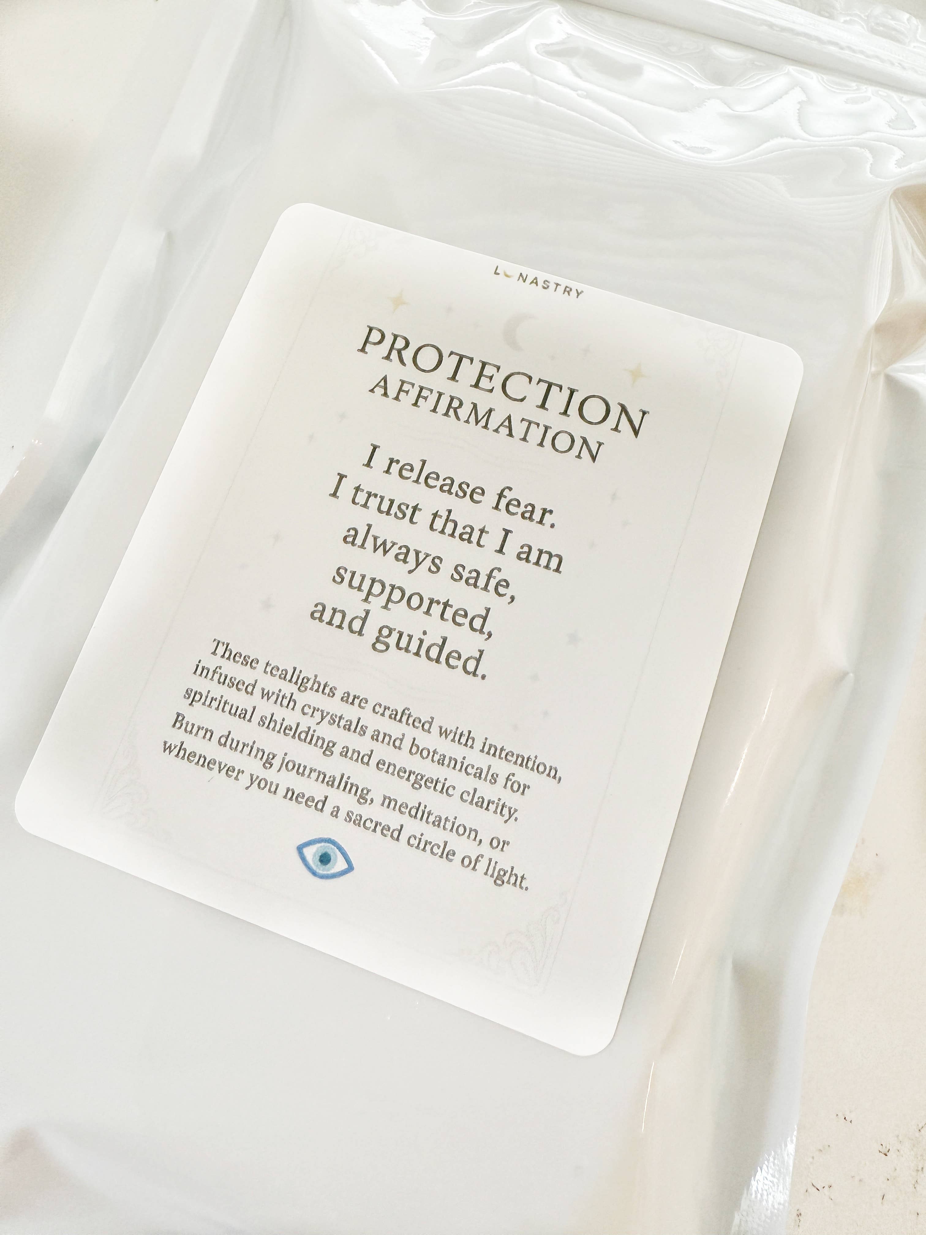 White candle with a 'Protection Affirmation' card on a white background