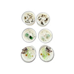 Six small tea light candles with decorative elements on a marble surface