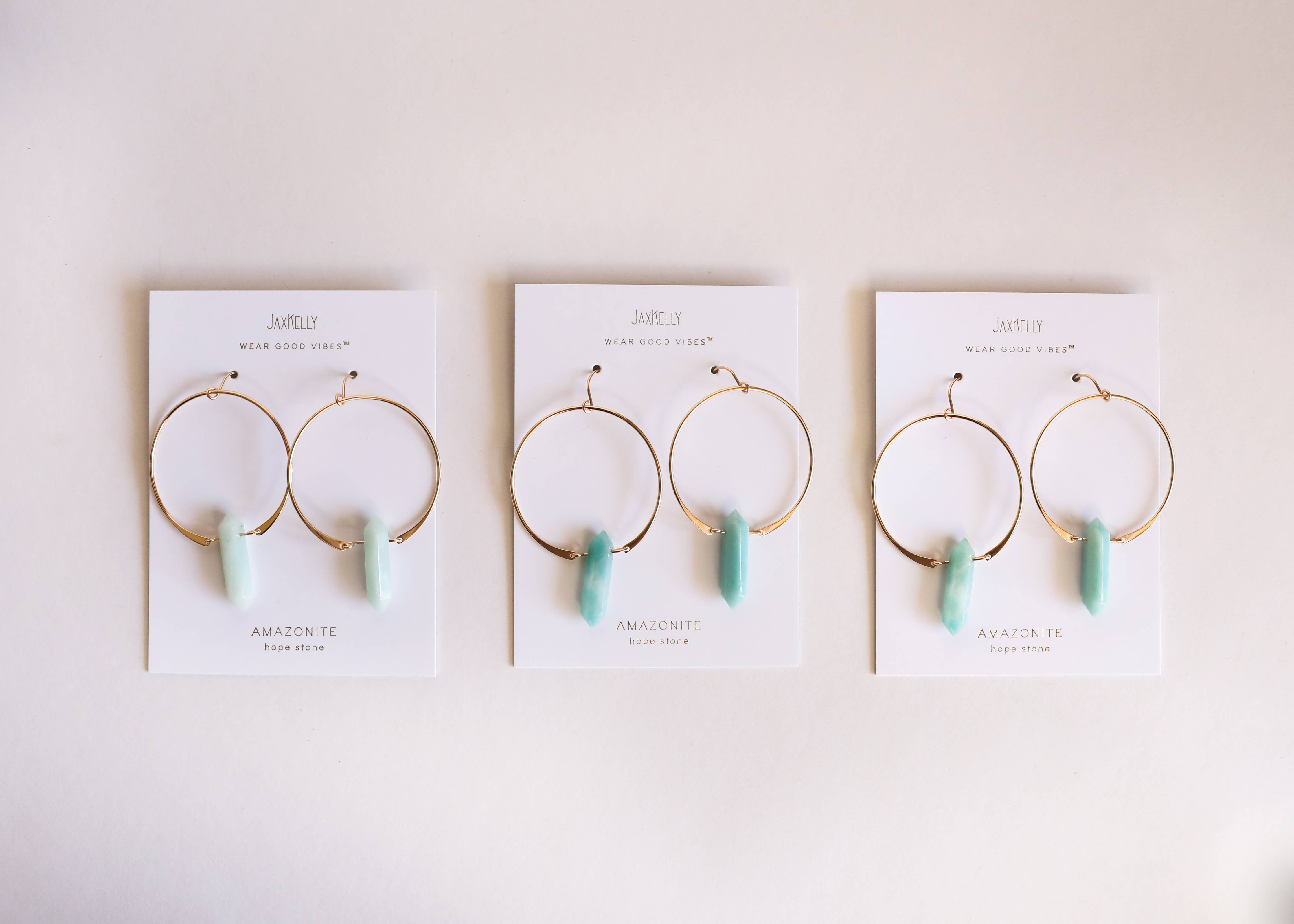 Three pairs of earrings on their cards with a white background
