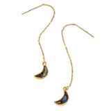 Gold earrings with blue crescent moon-shaped charms on a white background