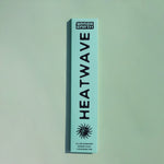 A tall, narrow mint-green box for Grass Earth Heatwave incense sticks, featuring bold black text and a sun graphic, set against a matching mint-green background.