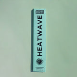 A tall, narrow mint-green box for Grass Earth Heatwave incense sticks, featuring bold black text and a sun graphic, set against a matching mint-green background.