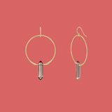 Gold hoop earrings with smoky quartz stones on a pink background