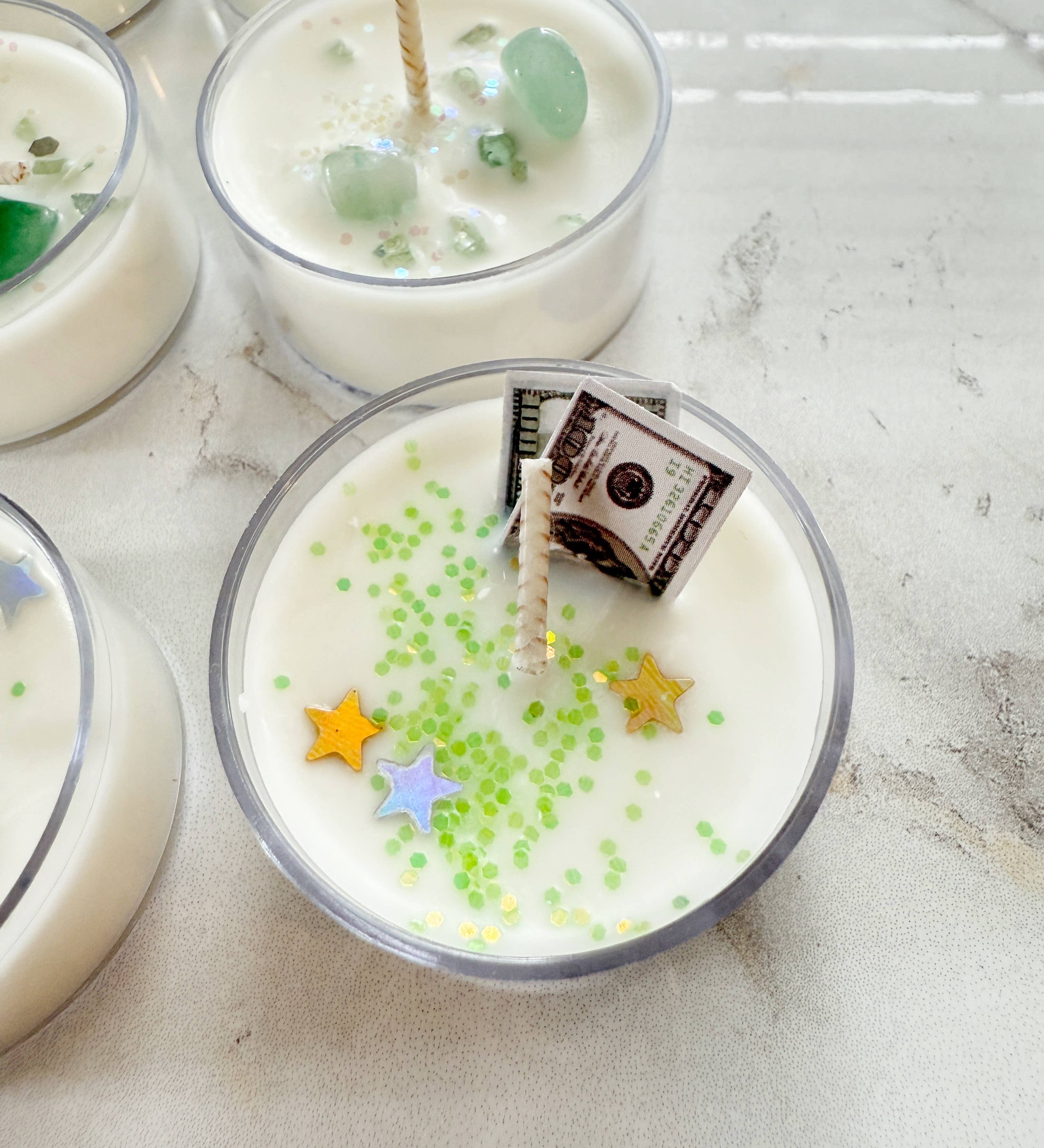 Candle with decorative stars and a small bag inside on a light surface