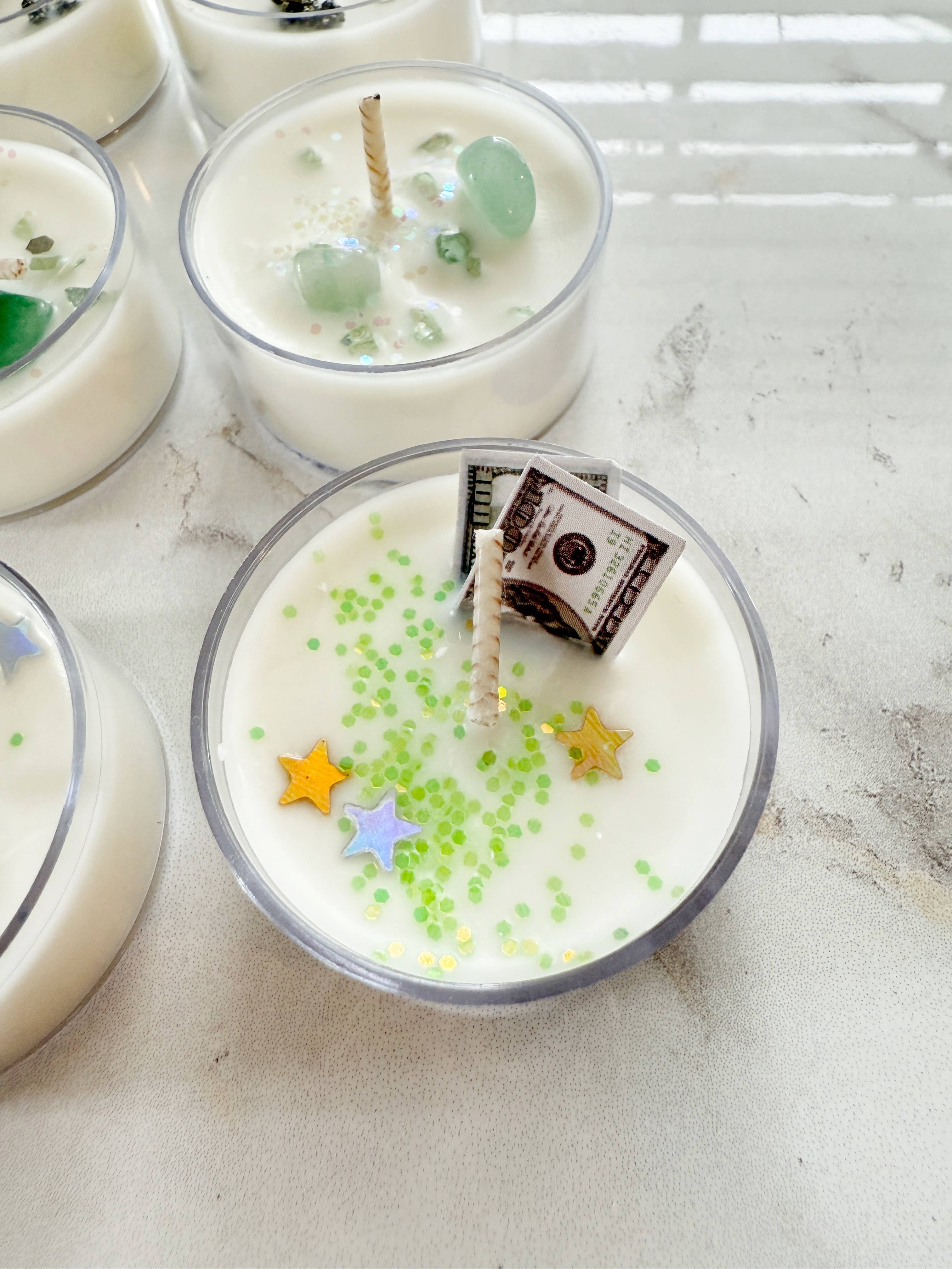 Candle with decorative stars and a small bag inside on a light surface