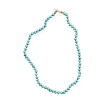 Turquoise beaded necklace on a light gray background