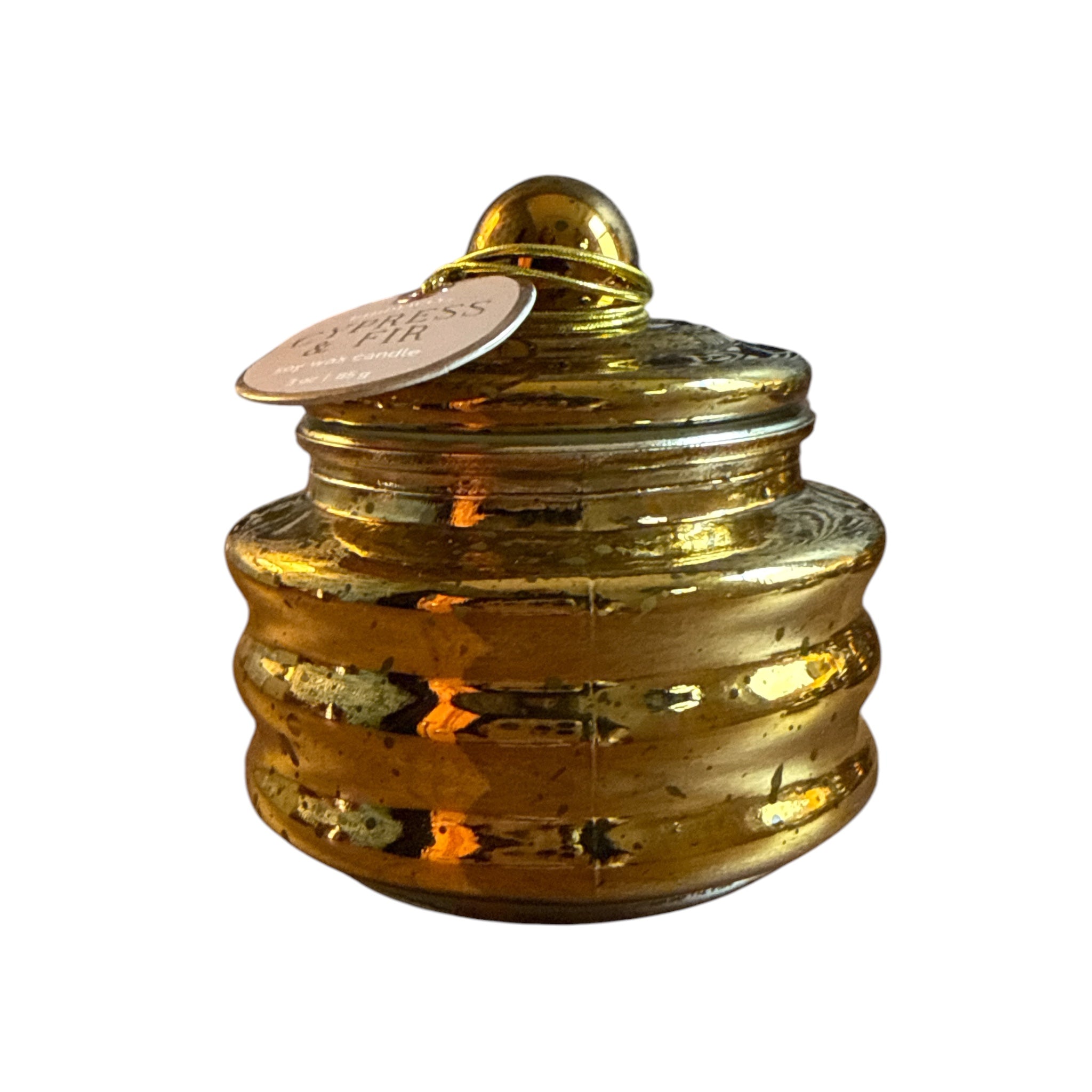 A small metallic gold lidded jar with a ribbed body and a hanging paper tag, photographed on a plain white background.