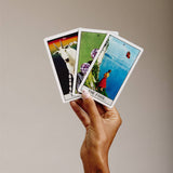 Hand holding three tarot cards against a plain background