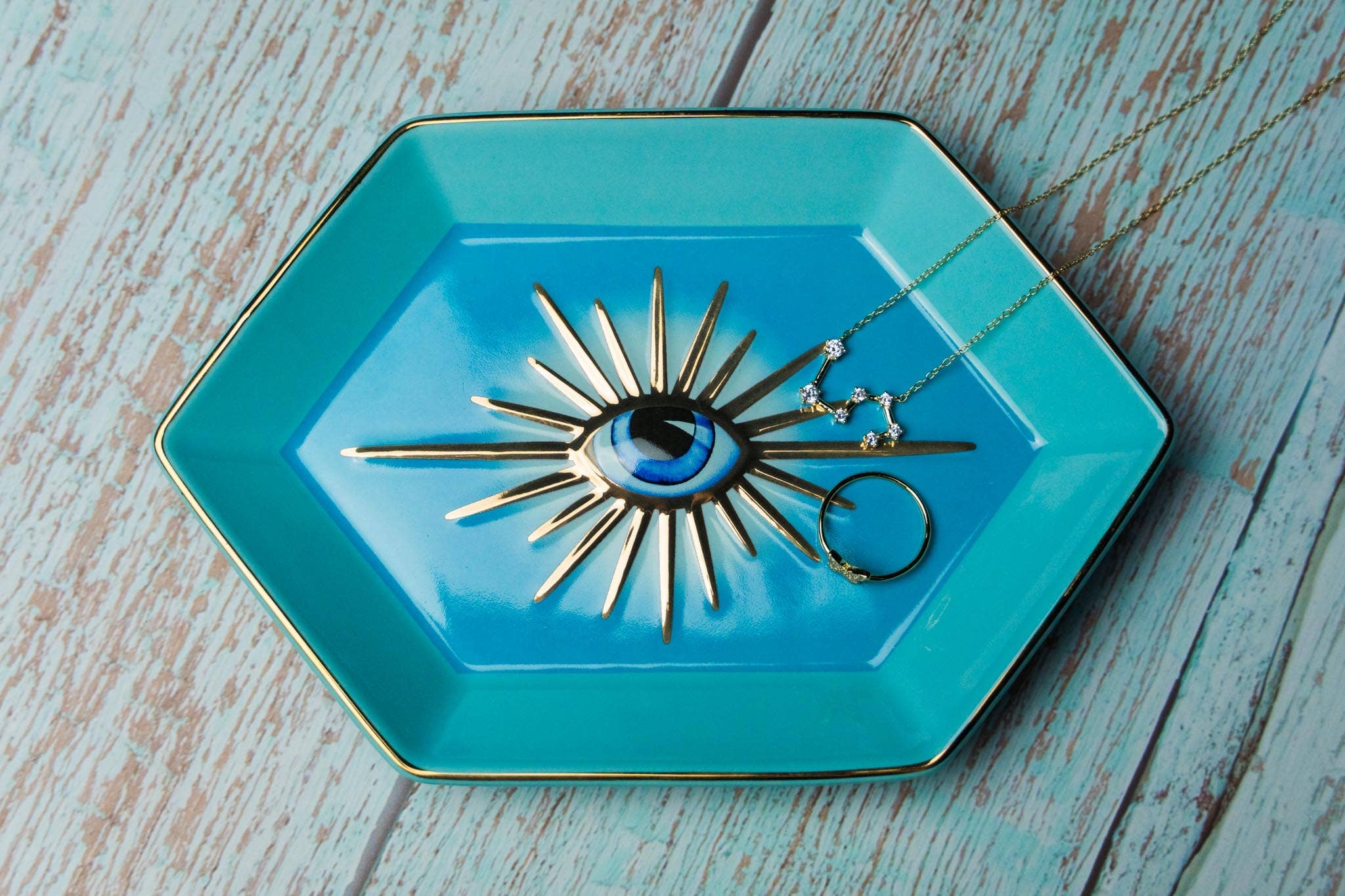 Turquoise jewelry dish with decorative necklace on a wooden surface