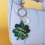 Green 'Lucky Clover' keychain on a light blue bag with a yellow background