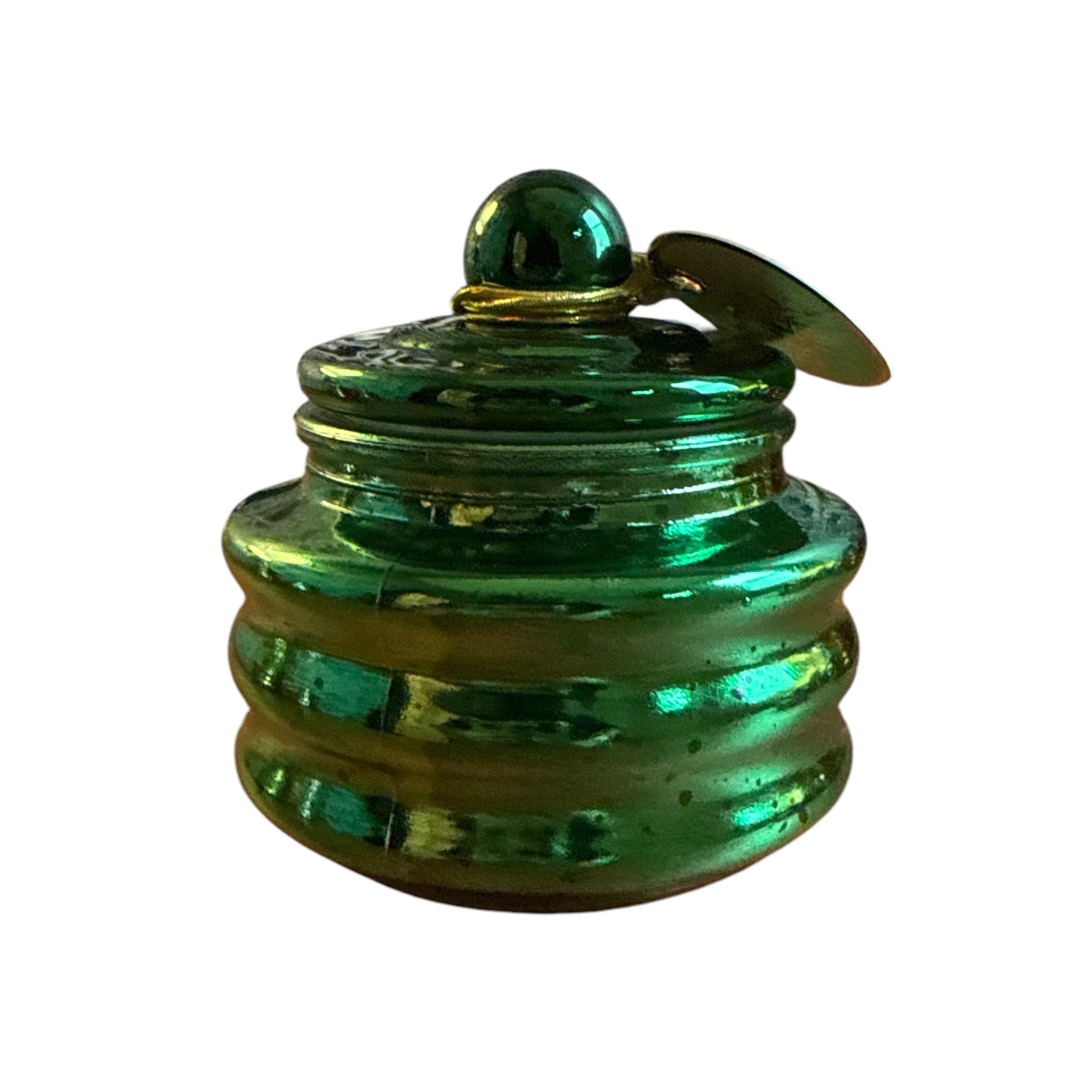 A small iridescent green glass jar with a matching lid and a small hanging tag, shown on a plain white background.