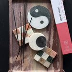 Decorative items including stones with checkered patterns and incense sticks on a wooden tray, with a box labeled 'Hokkaido Island' in the background.