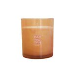 A Capricorn scented candle in a translucent amber glass jar, featuring a white wick and white printed text on the front, set against a white background.