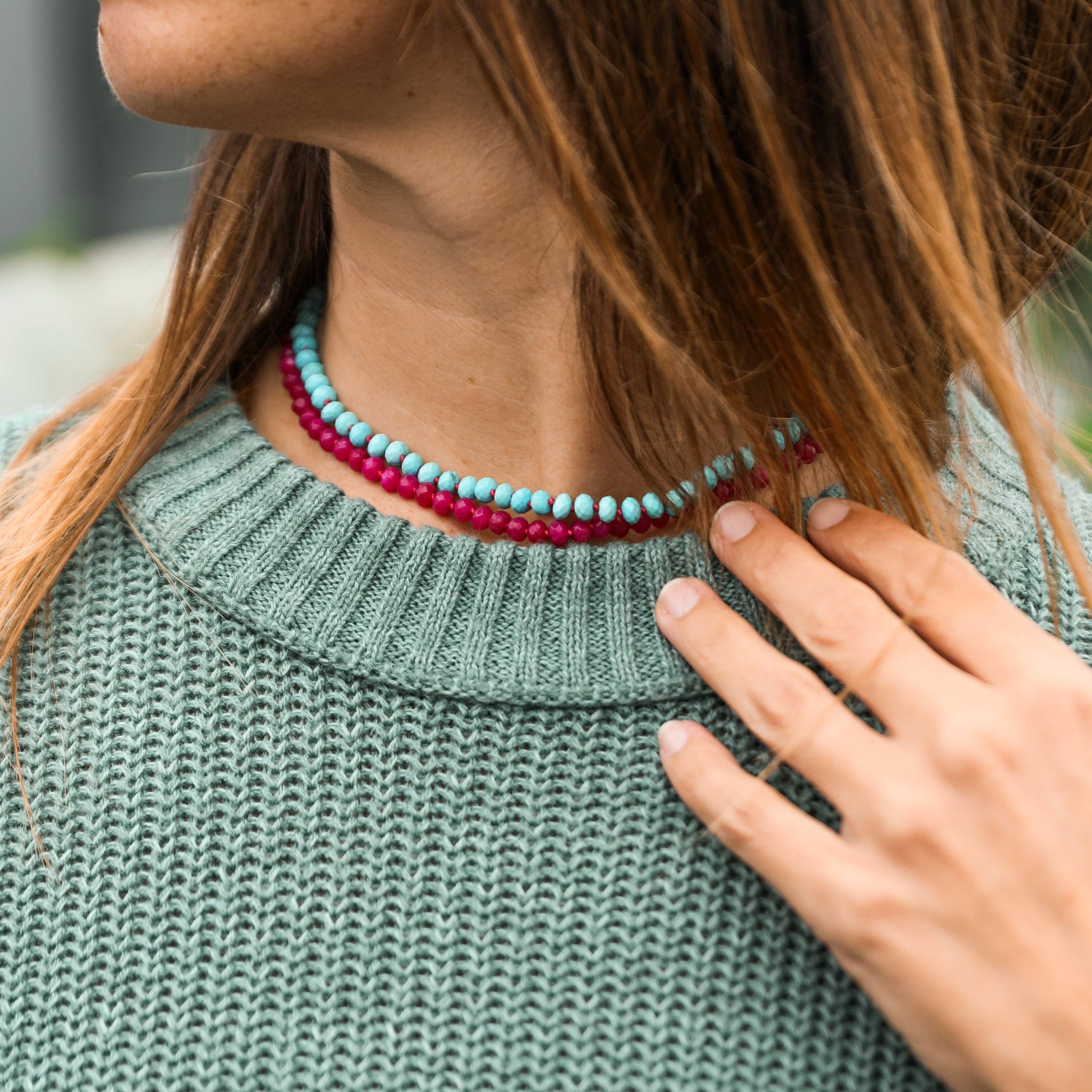 Person wearing a green sweater with a colorful beaded necklace