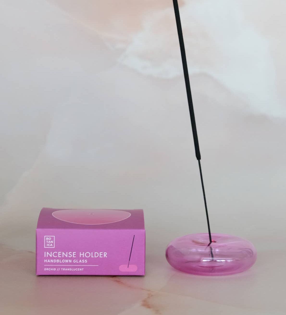Incense holder with a pink box on a light marble surface