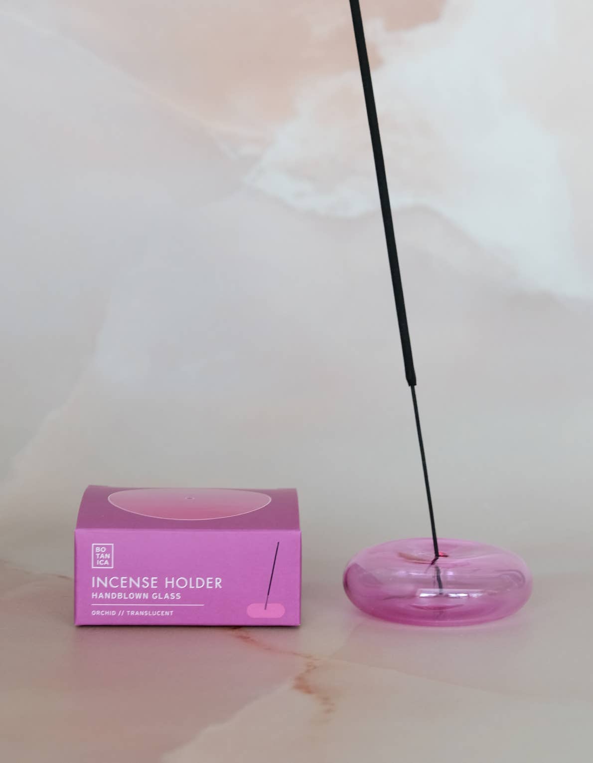 Incense holder with a pink box on a light marble surface