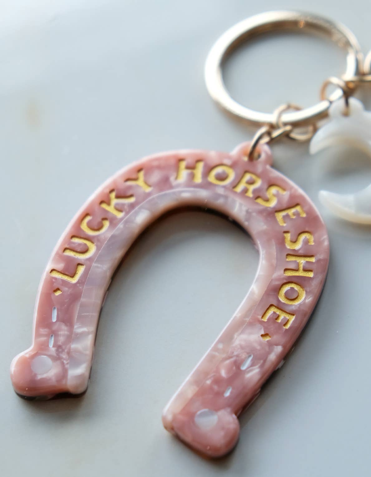 Pink horseshoe keychain with 'Lucky Horseshoe' text on a light background