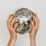 Hands holding a disco ball against a plain background