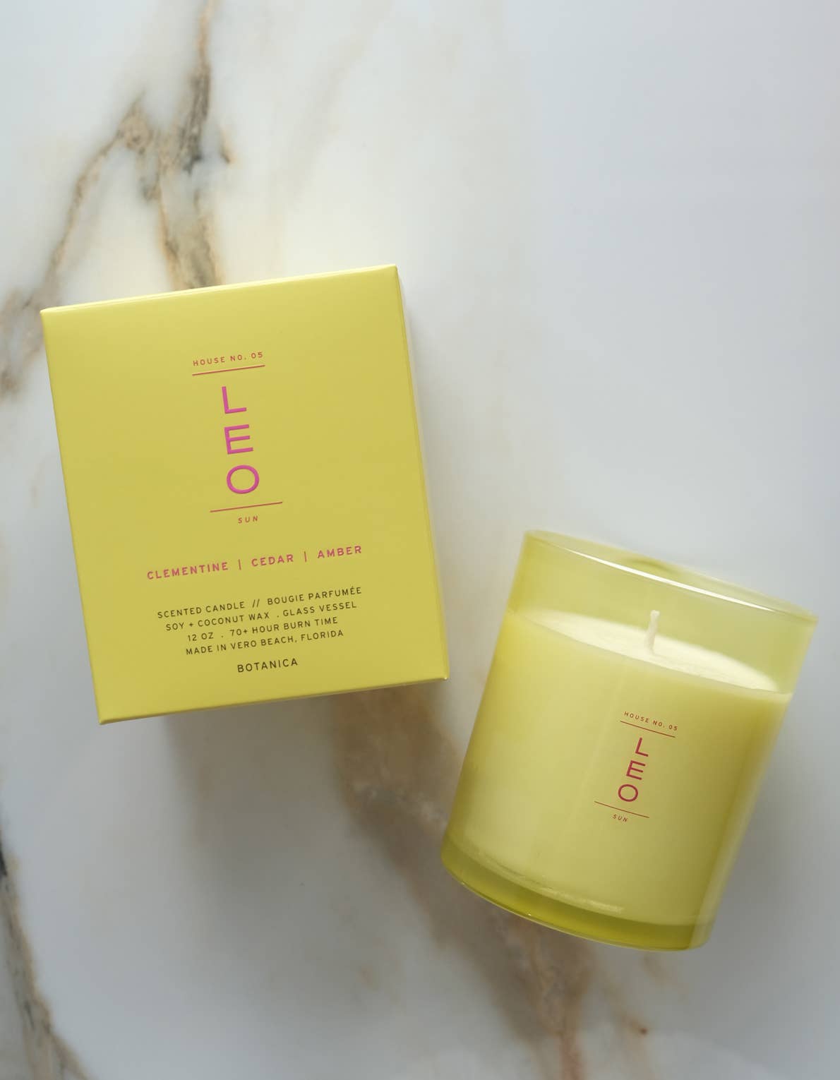 Yellow candle and box with 'LEO' branding on a marble surface