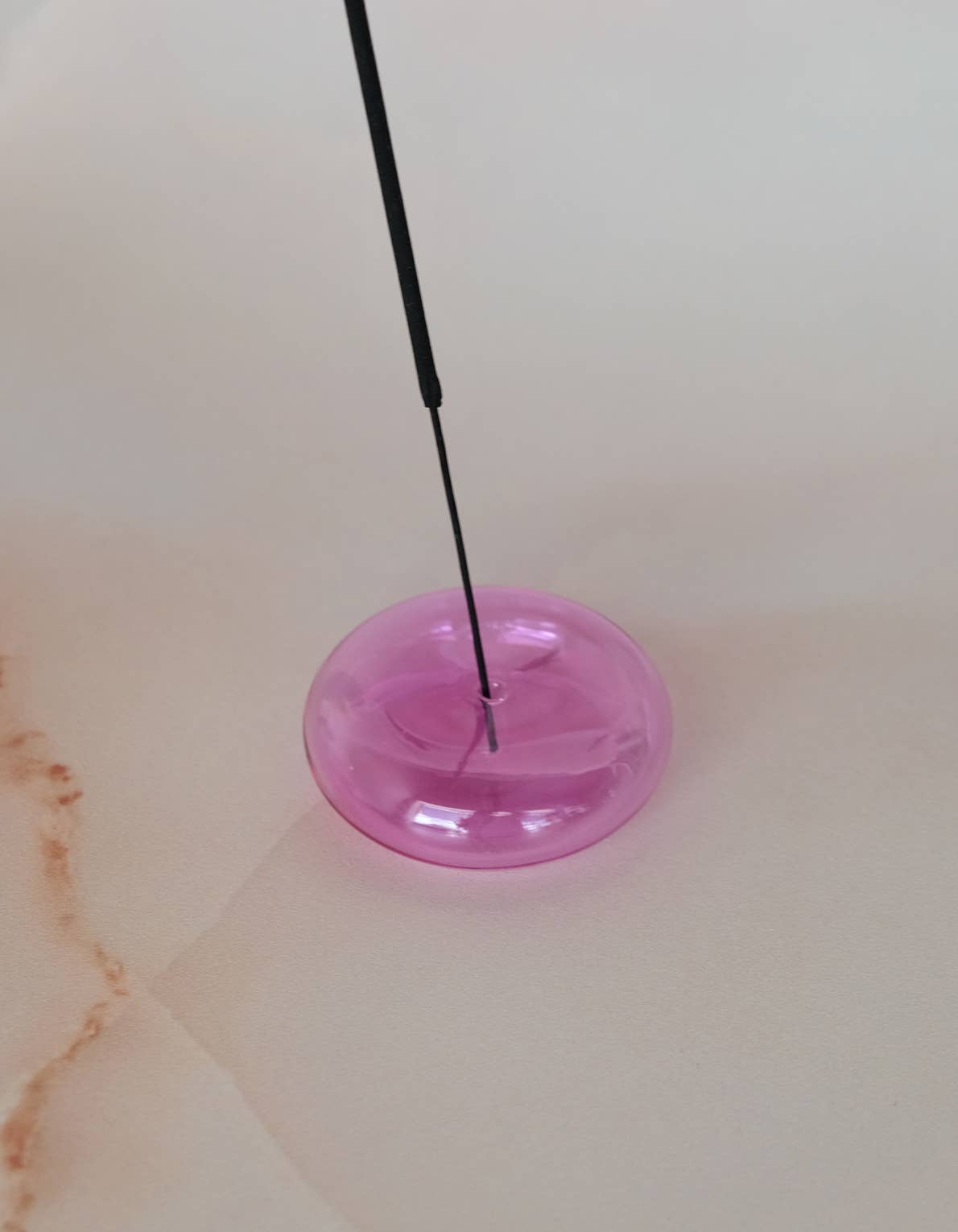 Pink object with a black rod on a light-colored surface