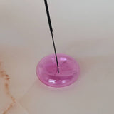 Pink object with a black rod on a light-colored surface