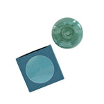 Teal glass incense holder on a blue box with a white background