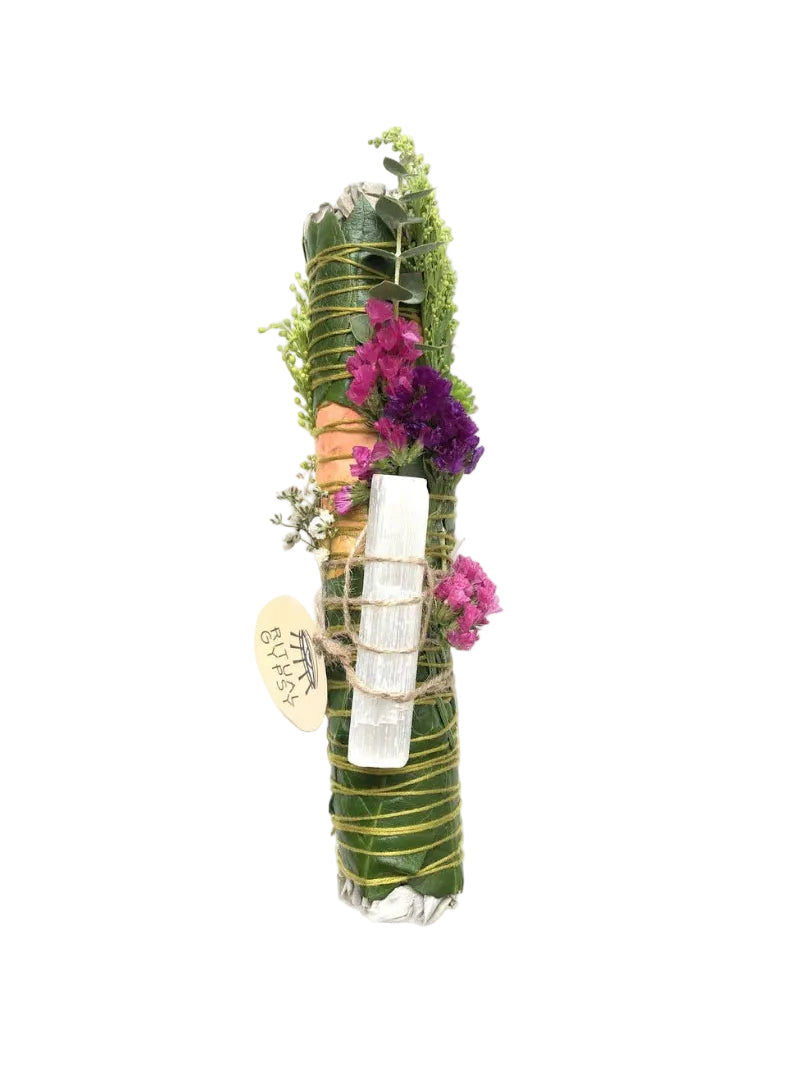 Decorative bundle with greenery, flowers, and a white candle on a white background
