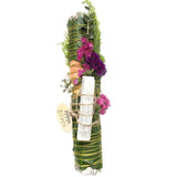 Decorative bundle with greenery, flowers, and a white candle on a white background