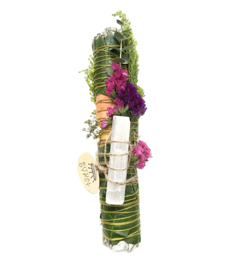 Decorative bundle with greenery, flowers, and a white candle on a white background