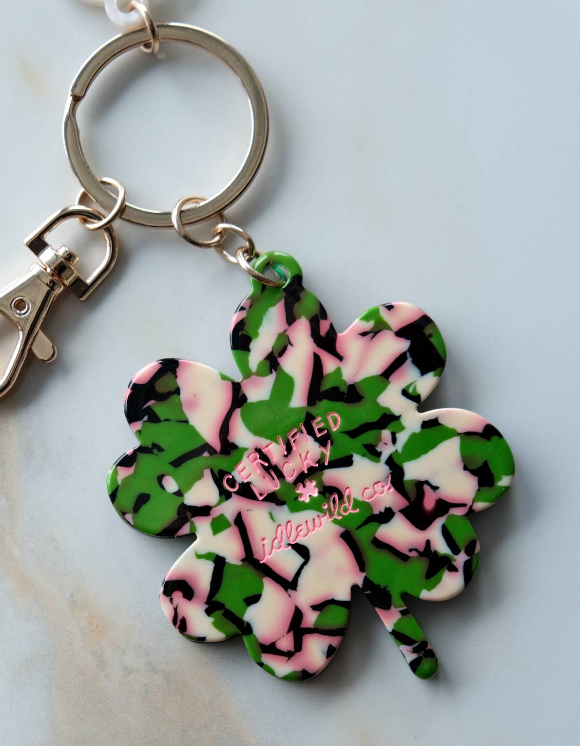 Keychain with a camouflage-patterned four-leaf clover design on a light background