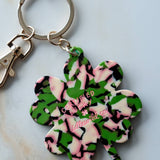 Keychain with a camouflage-patterned four-leaf clover design on a light background