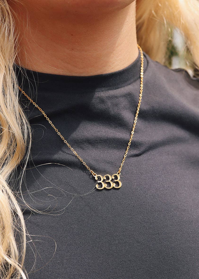Gold necklace with a unique design worn by a person against a black background