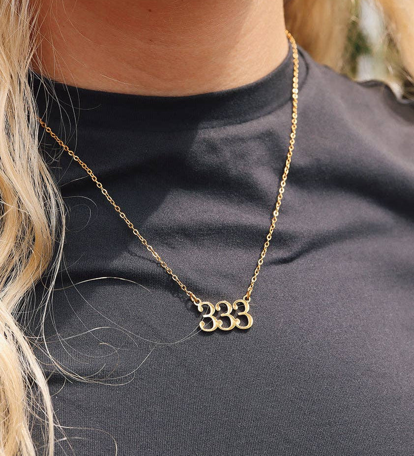 Gold necklace with a unique design worn by a person against a black background