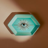 Hexagonal turquoise dish with eye design on a brown background