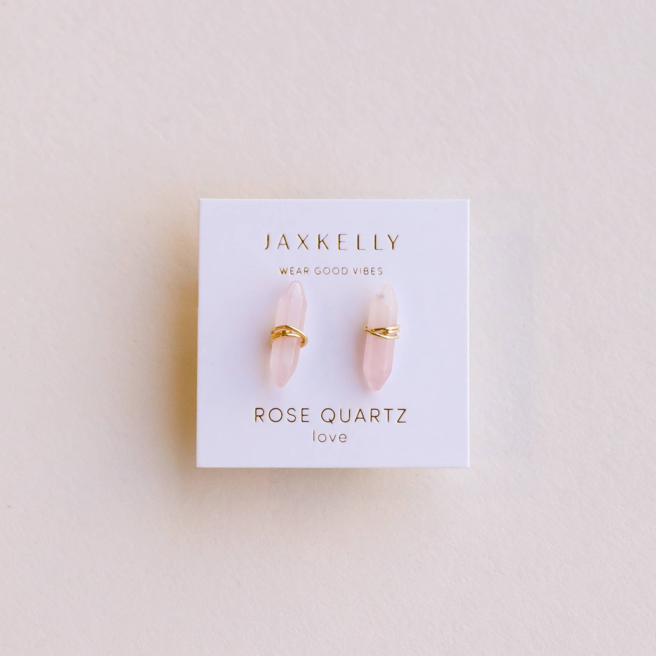 Jax Kelley rose quartz earrings on a branded card against a light background