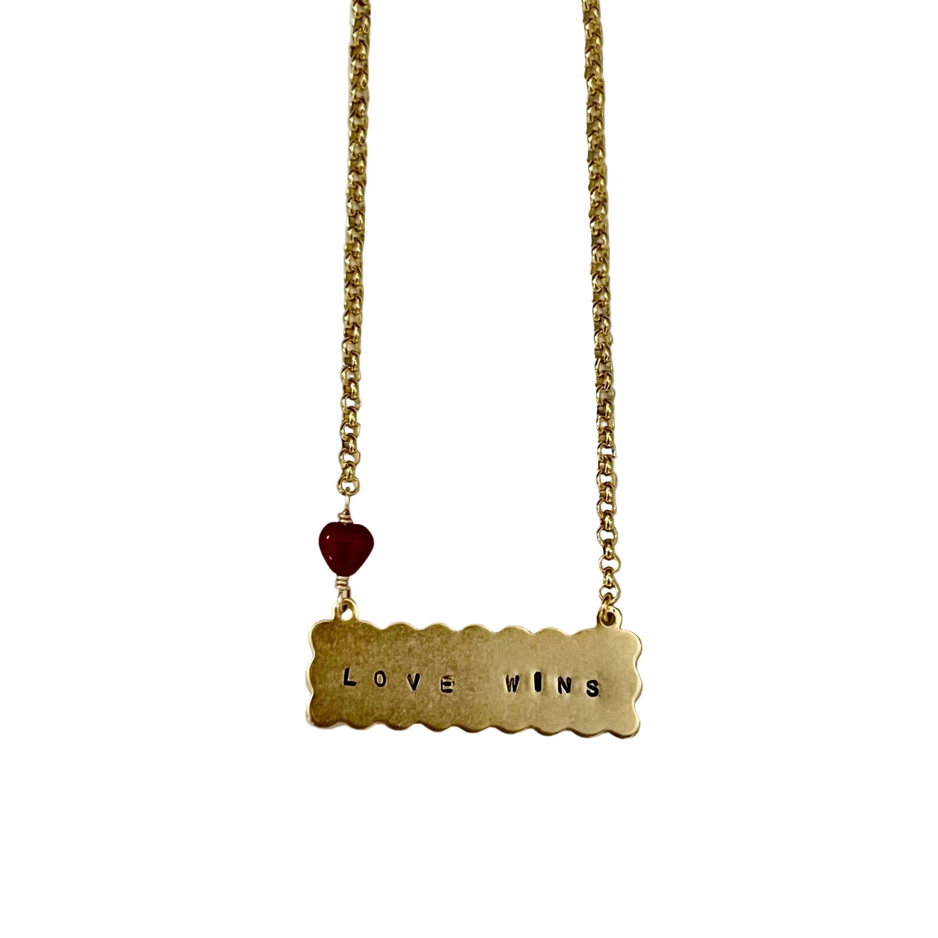 Gold necklace with 'LOVE WINS' pendant on a light gray background