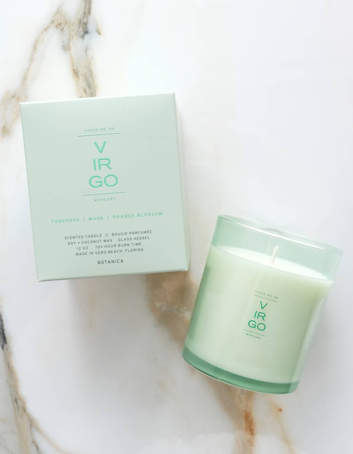 Green candle and packaging on a marble surface