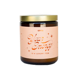 Candle with a gold lid and pink label on a white background