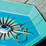 Jewelry including a necklace, earrings, and a decorative eye-shaped object on a turquoise plate.