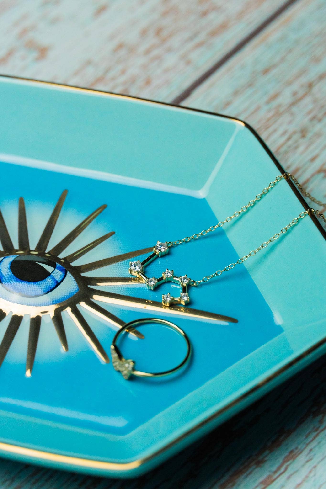 Jewelry including a necklace, earrings, and a decorative eye-shaped object on a turquoise plate.
