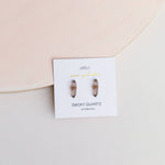 Smoky quartz earrings on a branded card with a pink background