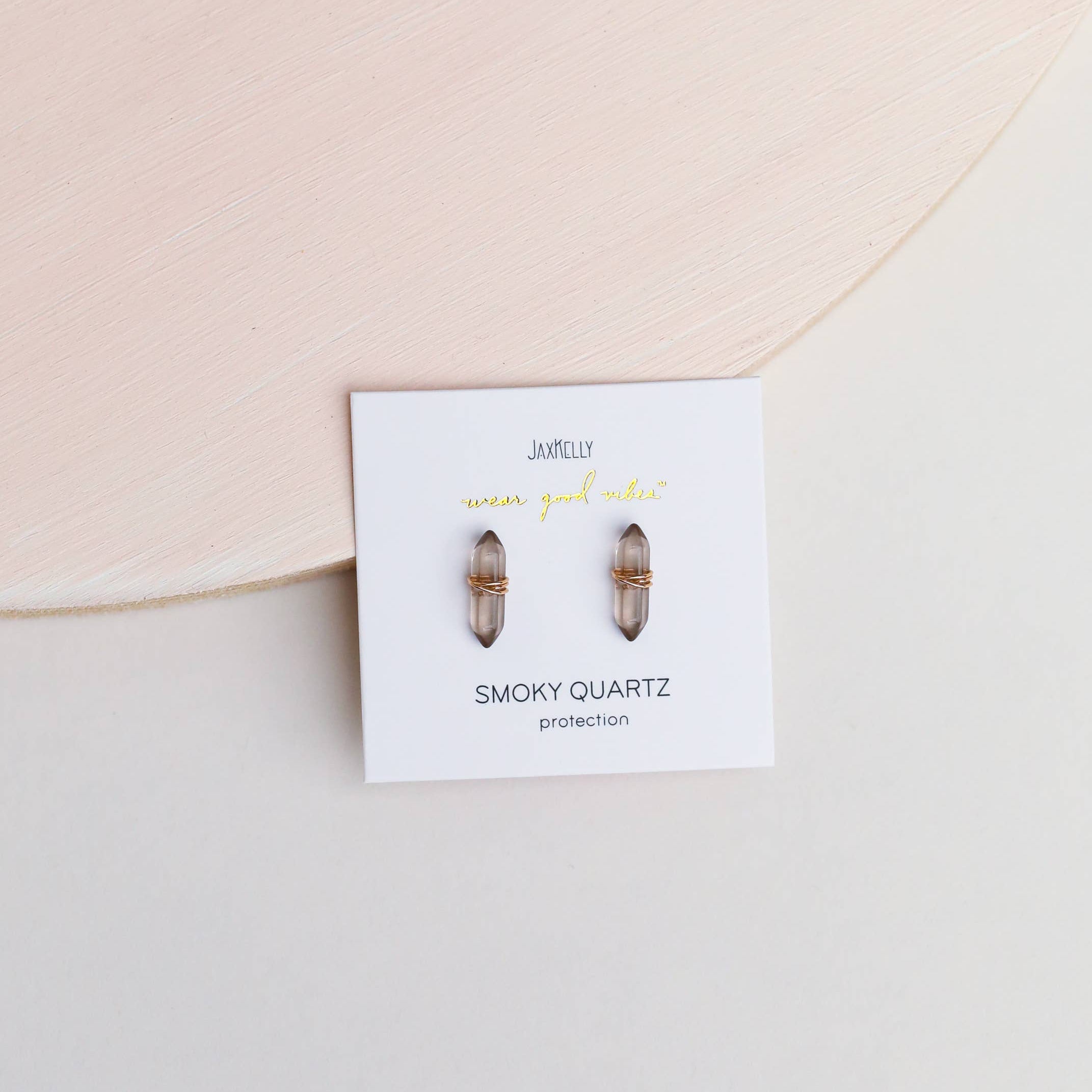 Smoky quartz earrings on a branded card with a pink background
