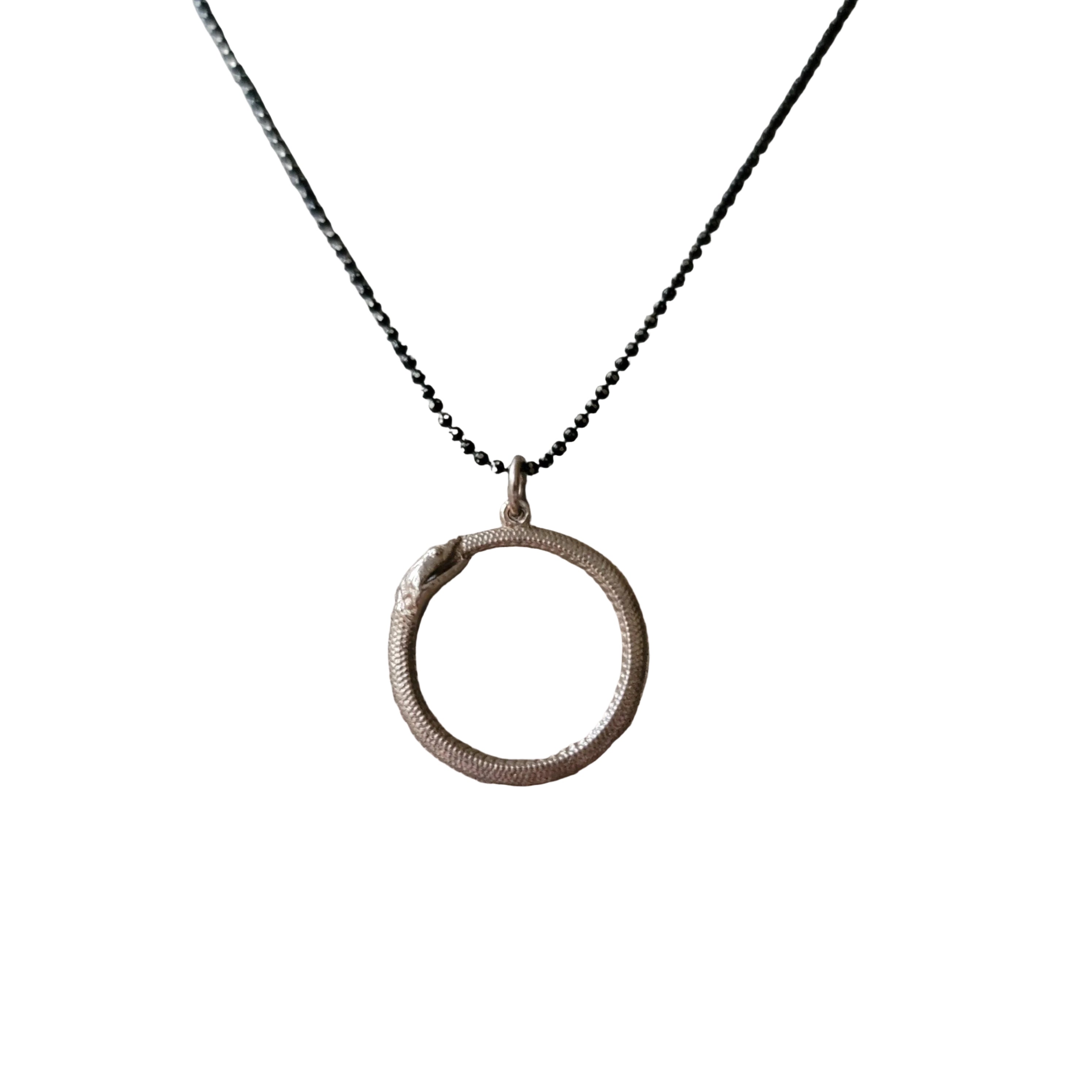 Necklace with a circular snake pendant on a white background