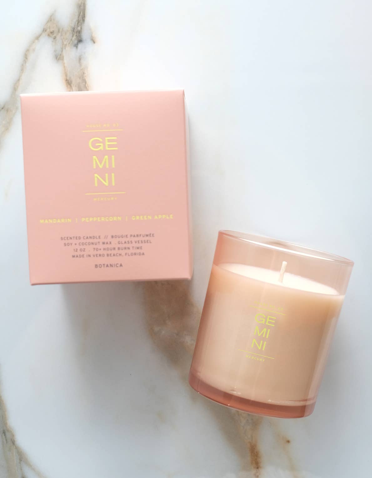 Candle and packaging with 'GEMINI' branding on a marble surface