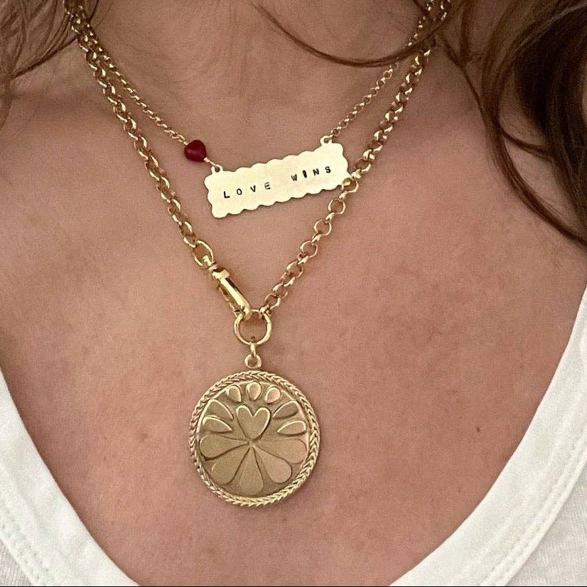 Woman wearing a gold necklace with a pendant against a plain background