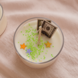 Candle with money and star-shaped decorations on a pink fabric background