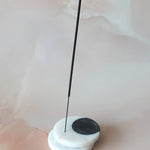 Incense stick on a white and black base with a plain background