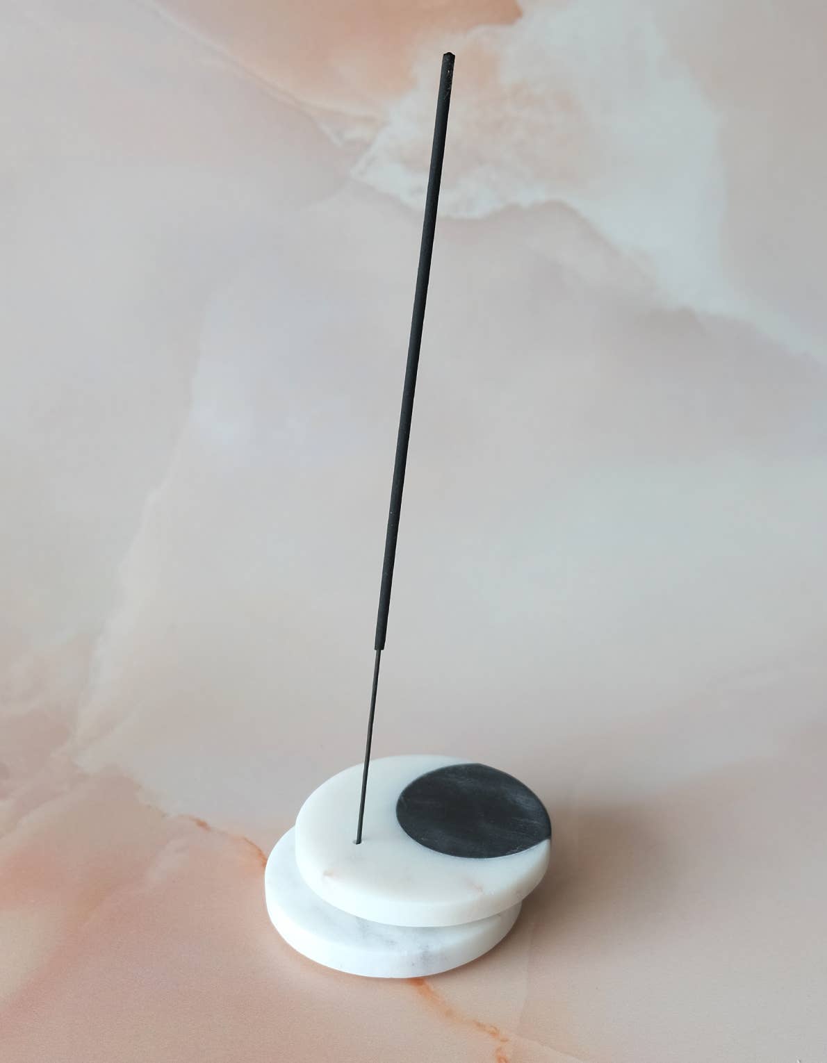 Incense stick on a white and black base with a plain background